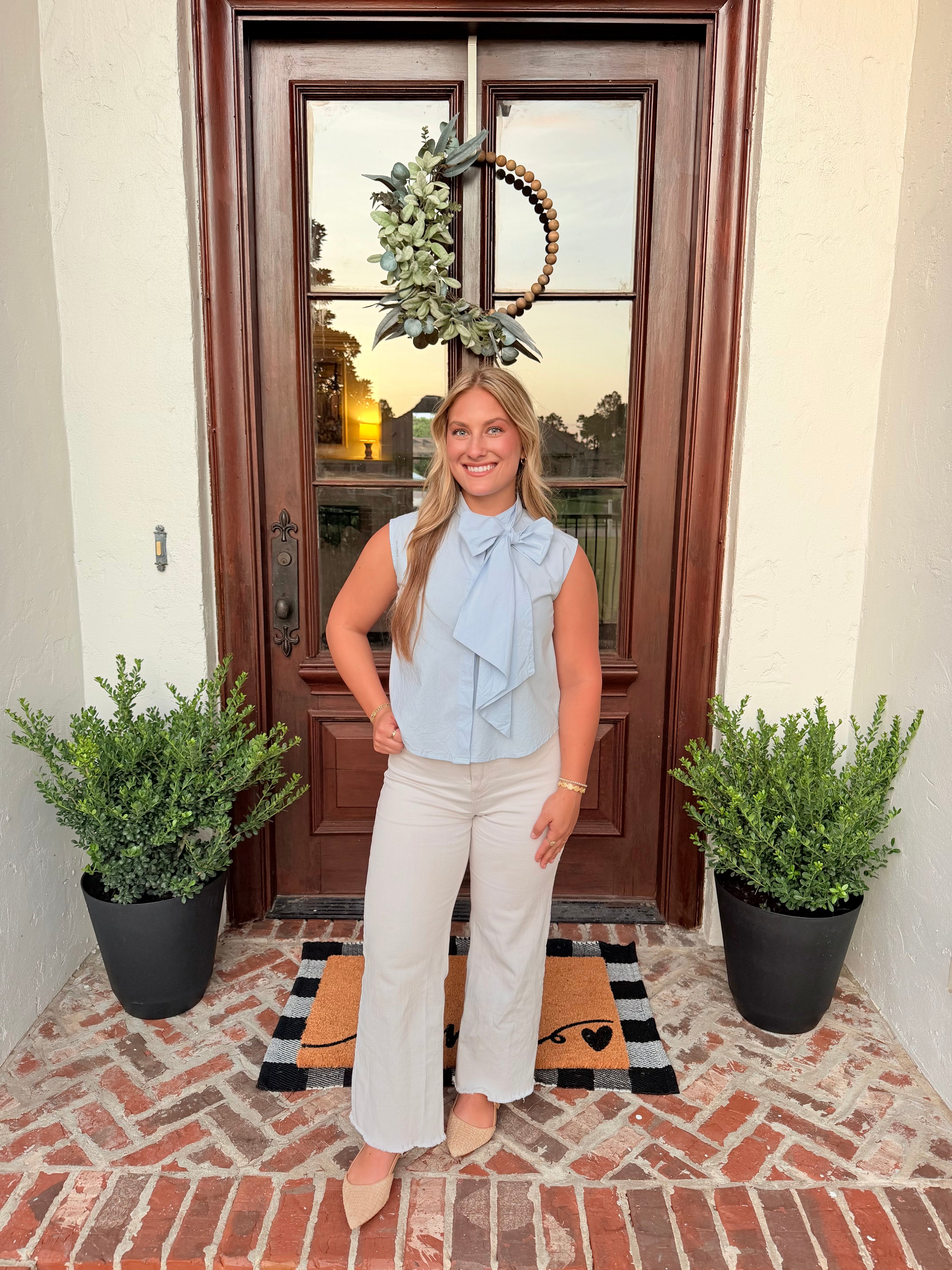 Sky blue sleeveless tie neck blouse with bow detail